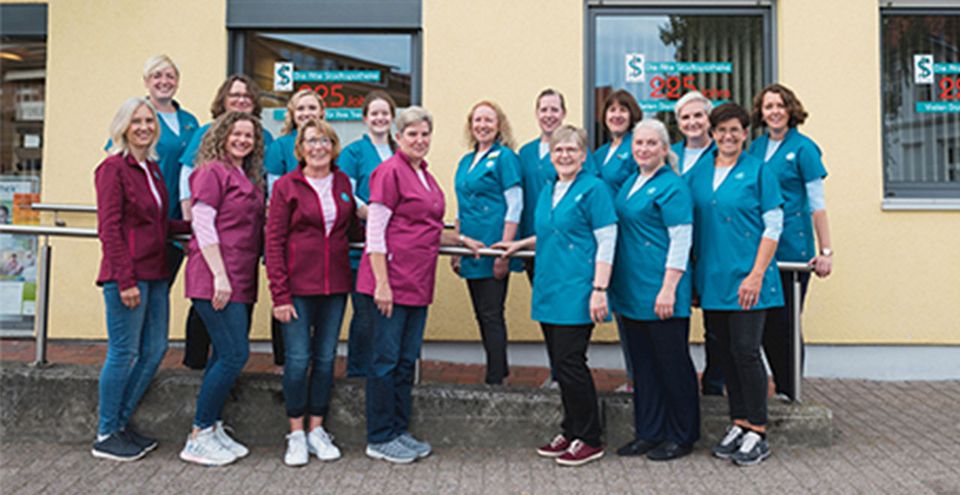Das gesamte Team steht vor dem barrierefreien Zugang der Apotheke.